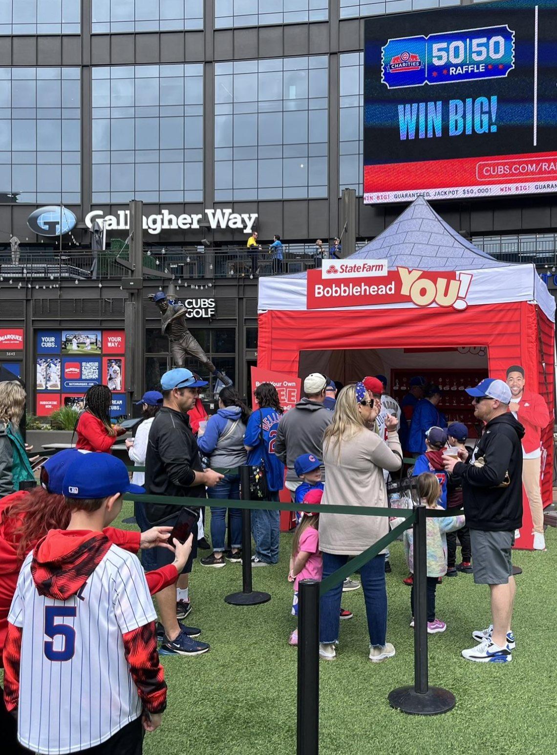 Fans lined up at a red State Farm Bobblehead You! tent on Gallagher Way, outside Wrigley Field.
